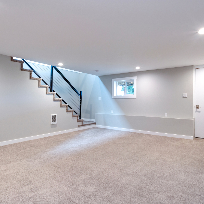 an empty basement with stairs and a window